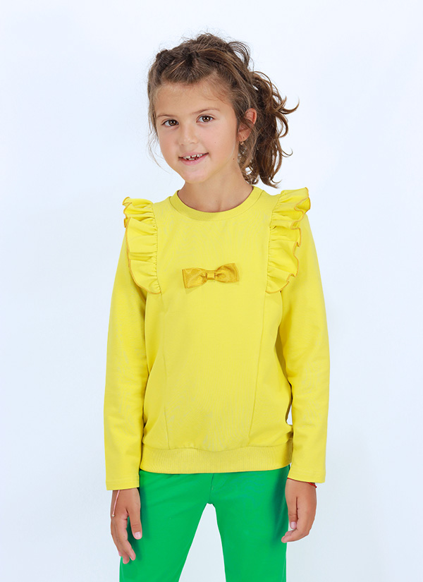 Блуза с къдри и панделка е класически модел с подгъв на ръкавите и маншет на талията. От средата на гърба към предната част минават къдри на раменете и прикачена панделка от сатен отпред. Блузата е в патешко жълт цвят, Момичета 3 - 7 години, Zinc