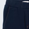 Долнище като панталон е със силуета на класическо долнище с ластик на талията но с подгъв на крачолите, два странични джоба и два задни джоба с цветни тегели. Отпред има имитация на шлиц. Долнището като панталон е в тъмно син цвят. Момчета 2 - 12 години, Zinc (отблизо)
